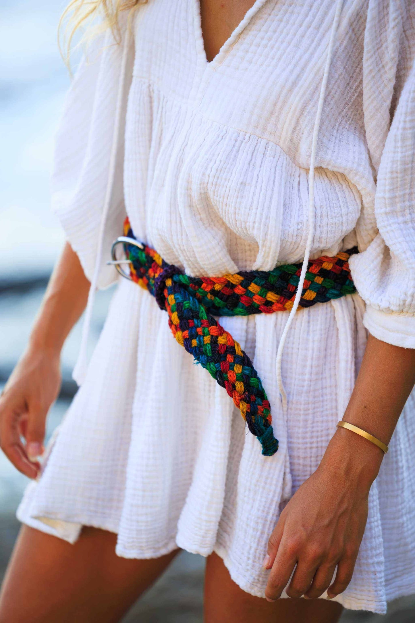 Handmade Himalayan hemp belt in braided multi-color rainbow style on a white dress.