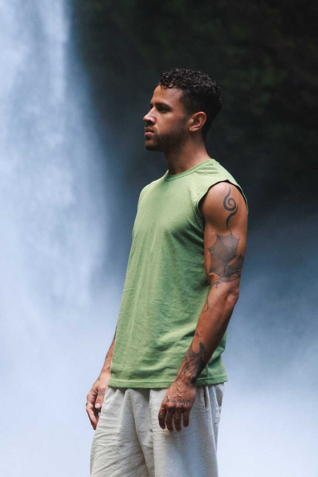 Man wearing a green hemp and organic cotton mens sleeveless shirt near a waterfall.