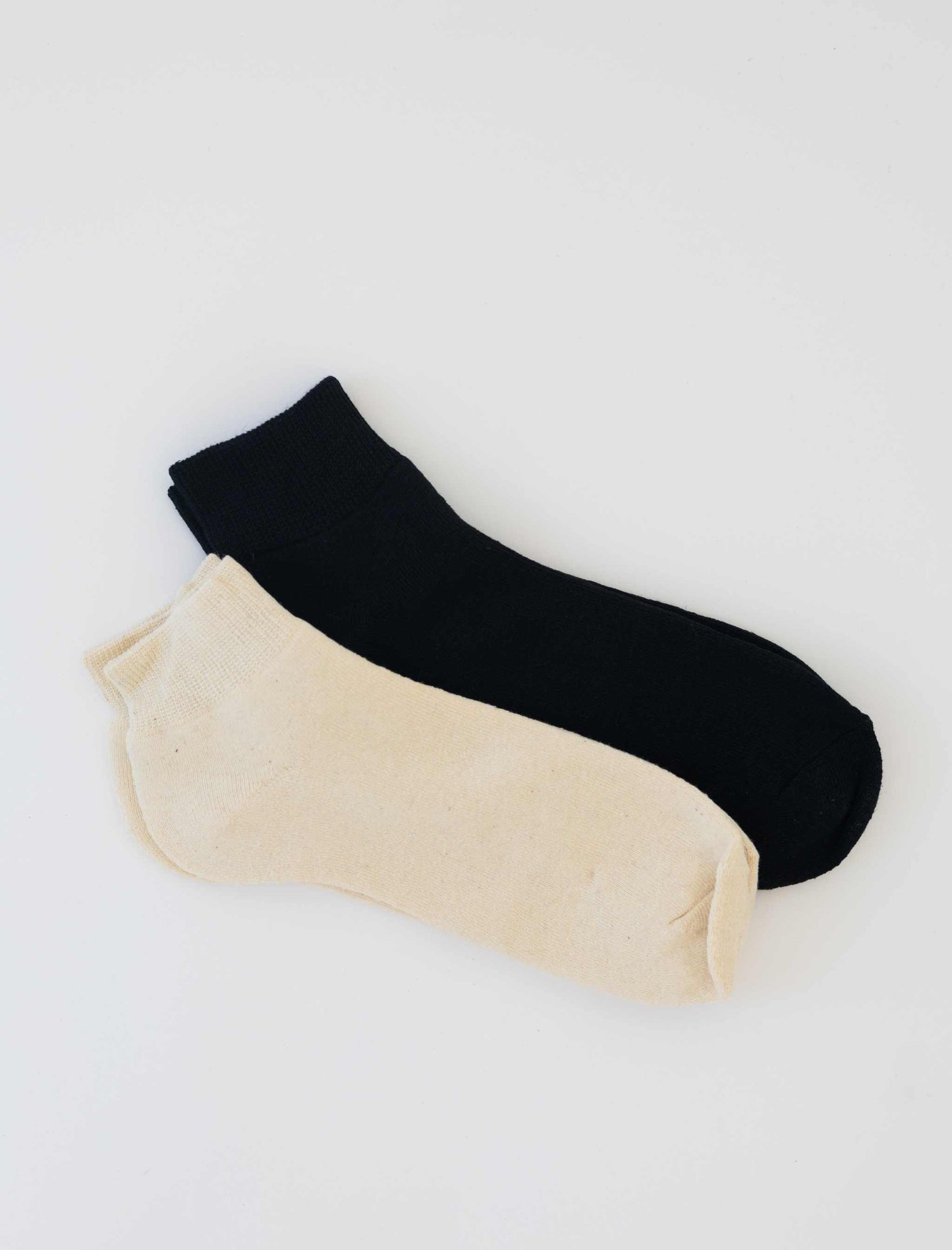 Pair of women's hemp socks in natural and black colors, ankle length, made from hemp and organic cotton blend.