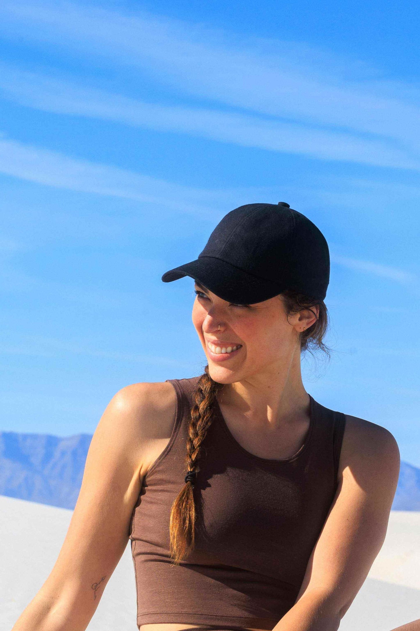Woman wearing black hemp and organic cotton baseball cap outdoors on sunny day