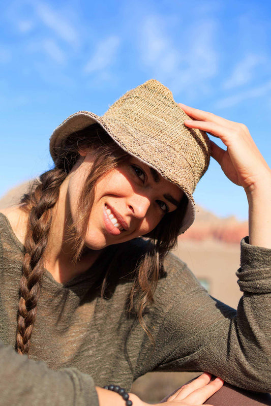 Hemp bucket hat in natural color worn by person outdoors with blue sky background.