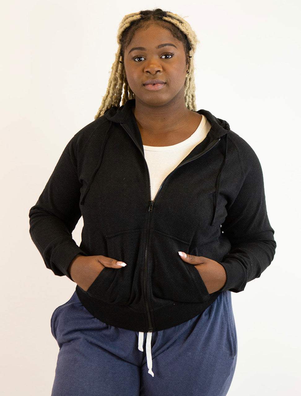 Woman wearing black hemp and organic cotton zip-up hoodie with front pockets and hood, styled casually
