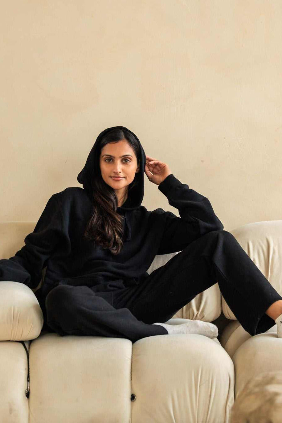 Woman in black outfit sitting on a beige sofa against a beige wall