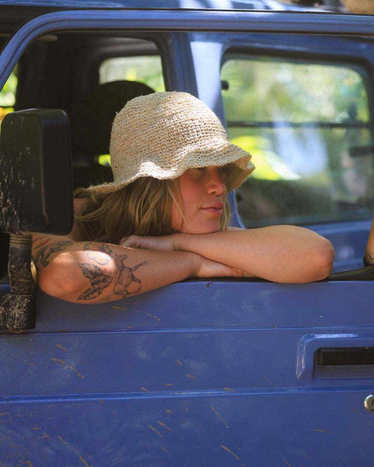 Hemp crochet floppy beach hat in natural color worn by a person sitting in a blue vehicle, showcasing boho style and foldable design.