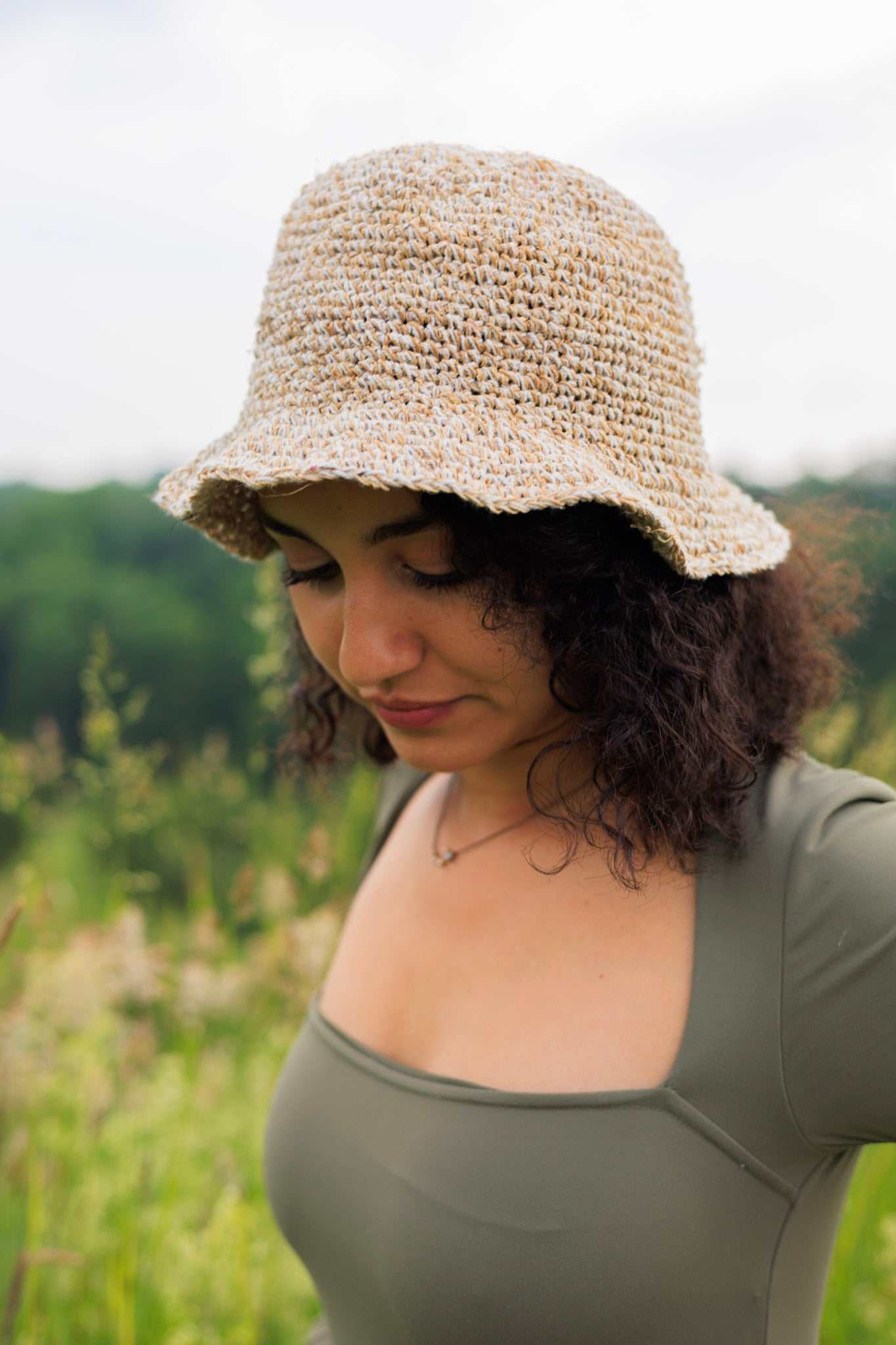 Woman wearing a beige crochet hat in a natural setting