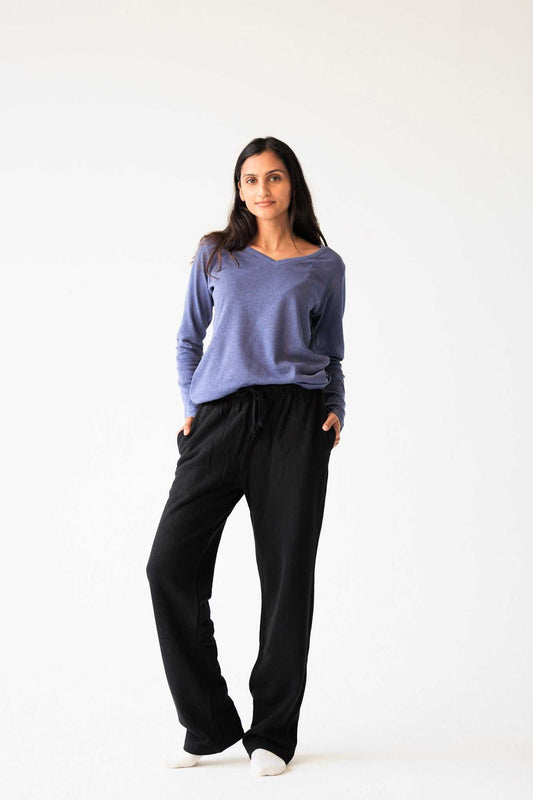 Woman wearing a purple sweater and black pants on a white background