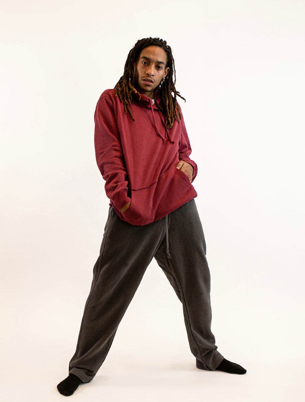Person wearing a red hoodie and gray pants on a white background