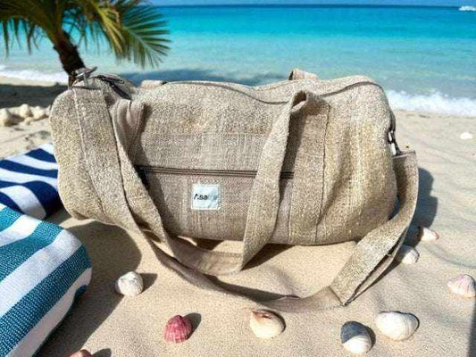 Eco-friendly hemp duffel bag with adjustable shoulder strap and spacious compartments on sandy beach near ocean