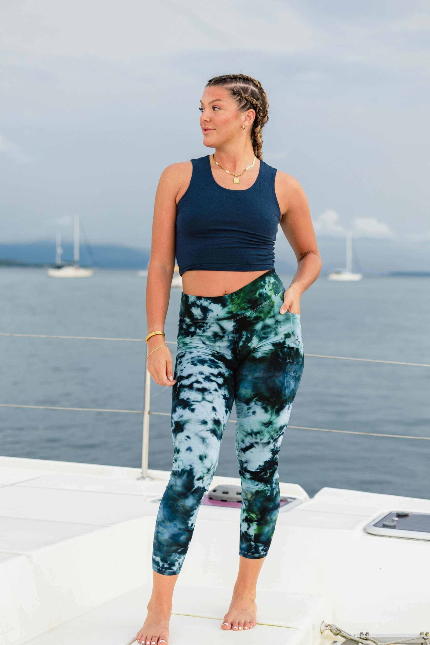 Woman wearing tie dye hemp pocket leggings and navy blue tank top outdoors by the sea