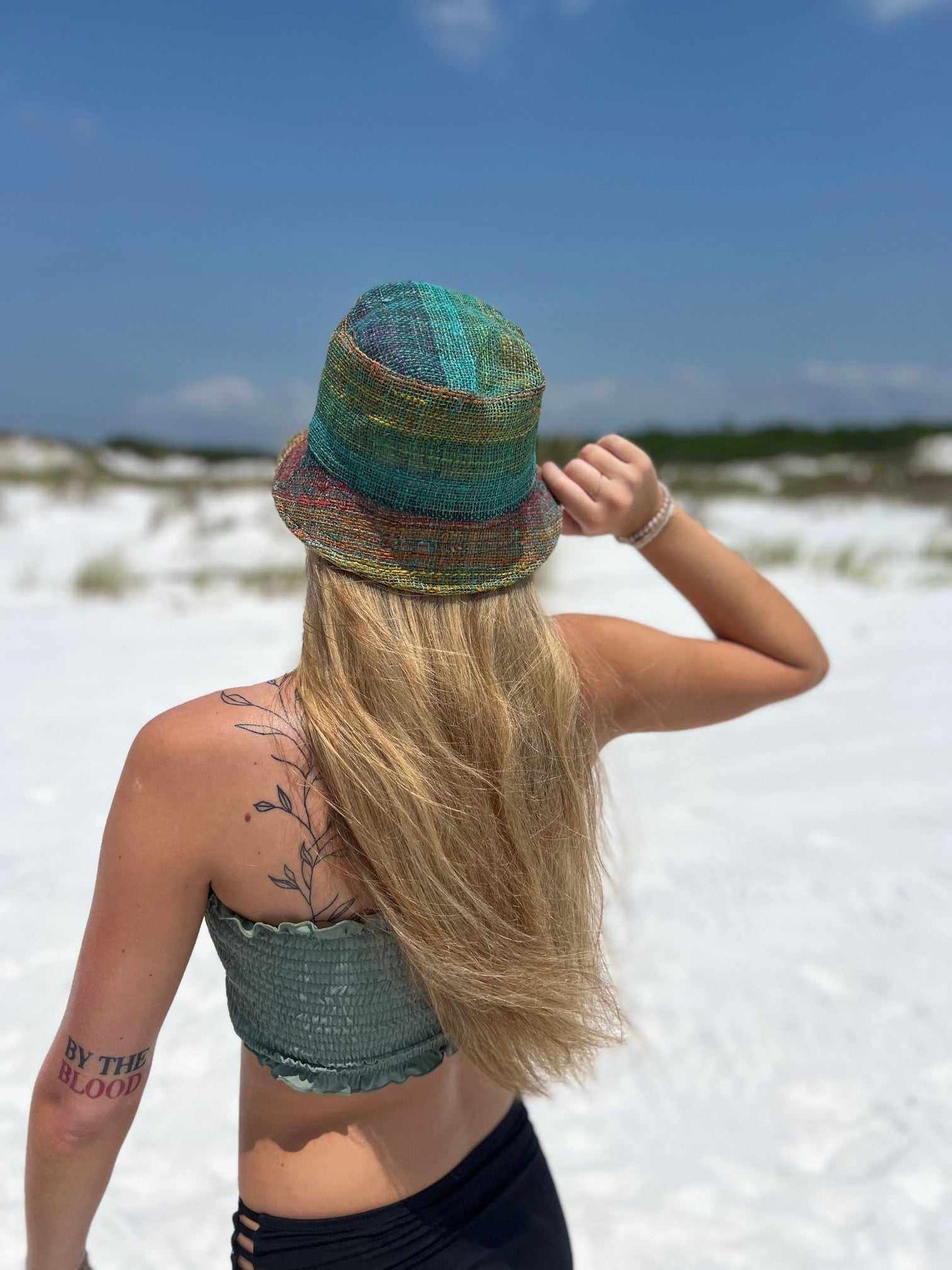 Rainbow bucket hat on woman outdoors, showcasing vibrant colors and sustainable style.