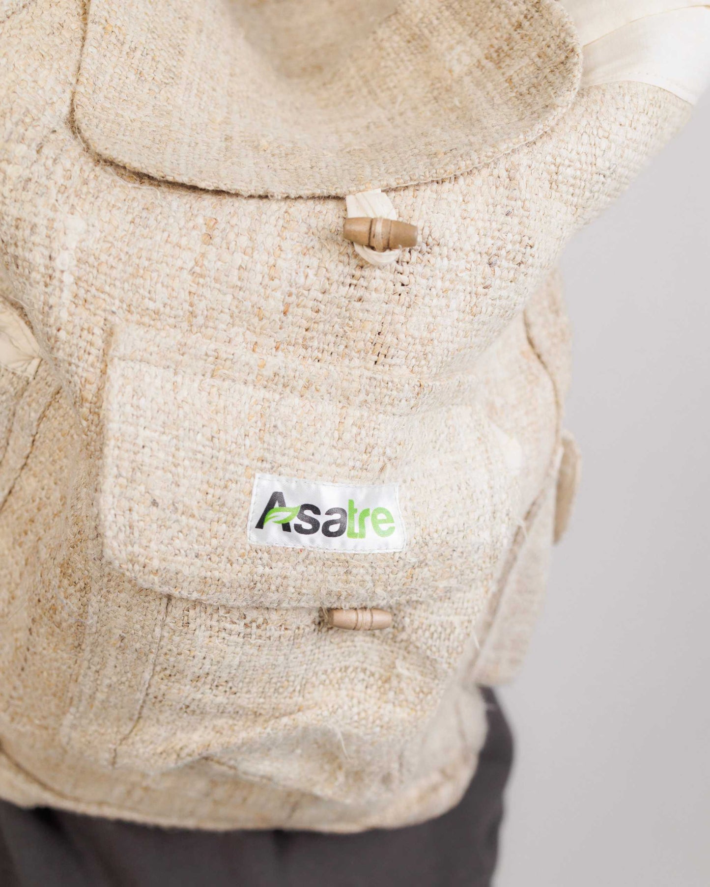 Beige textured hemp bag with a visible brand label on a light gray background