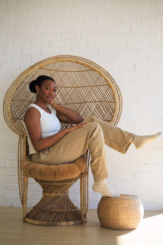 Woman wearing eco-friendly organic cotton fleece sweatpants sitting on wicker chair in cozy room