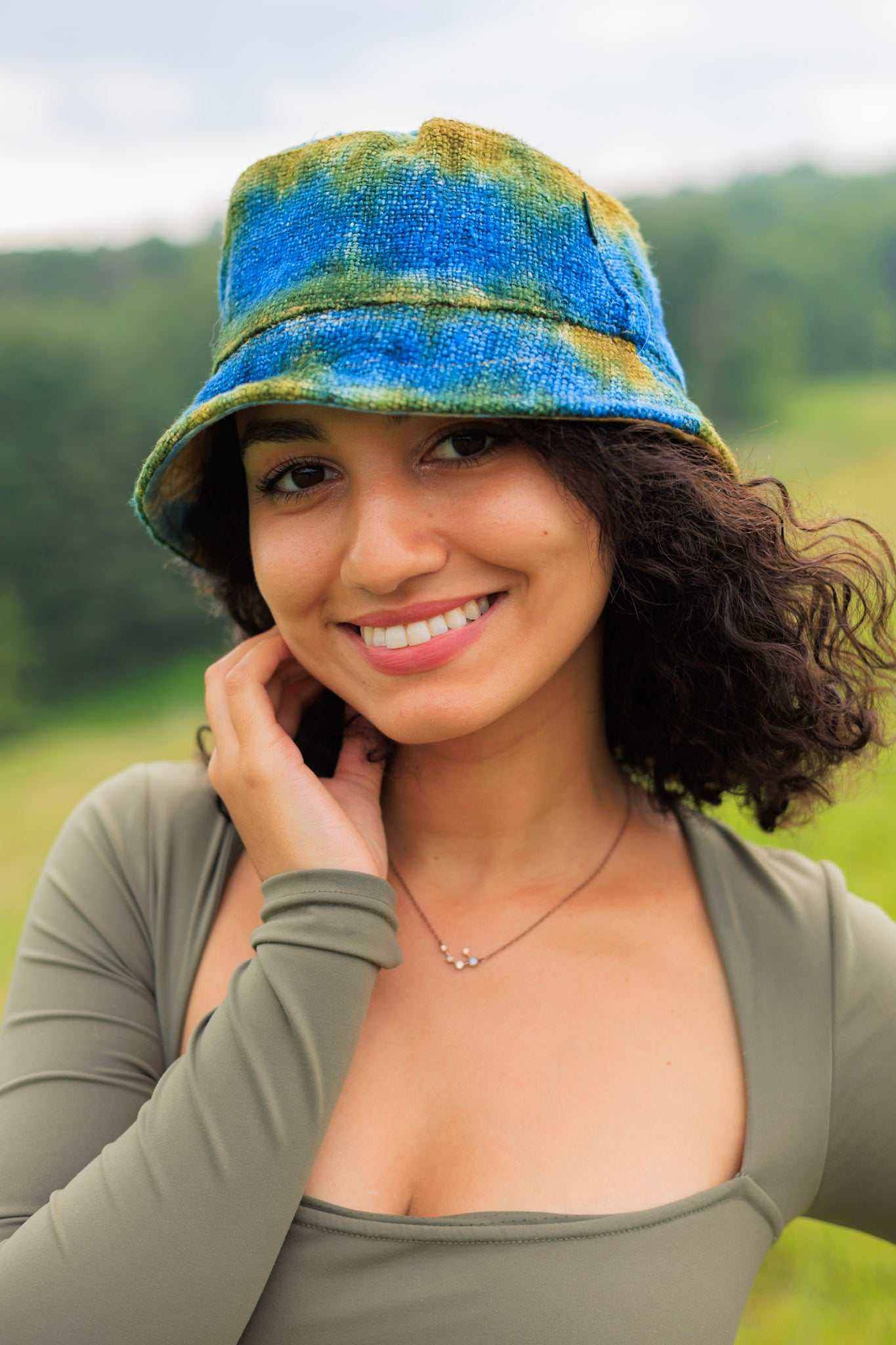 Tie dye bucket hat made from hemp in blue and green colors worn by a person outdoors.