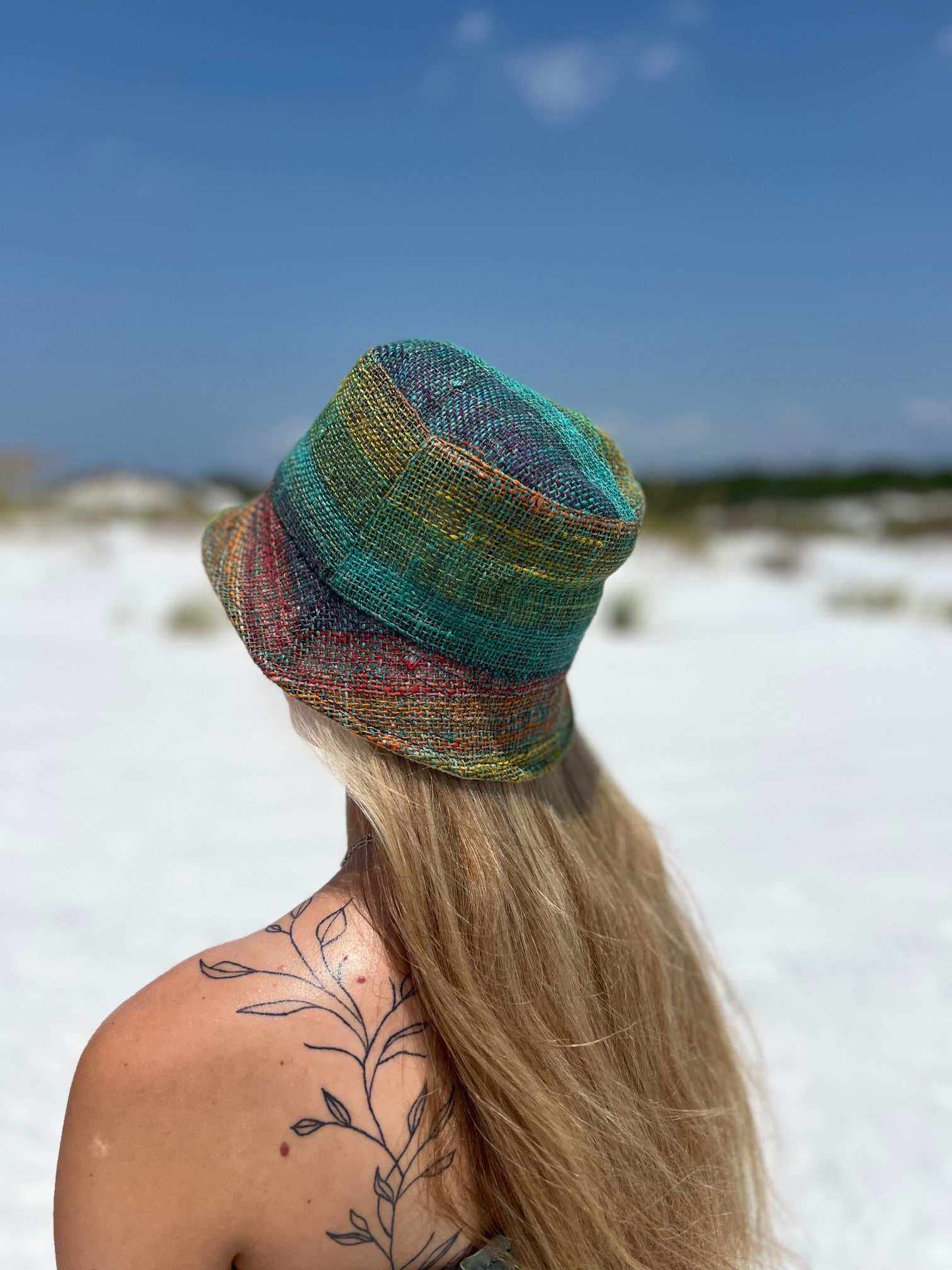 Rainbow hemp bucket hat on woman outdoors, showcasing vibrant colors and sustainable style.