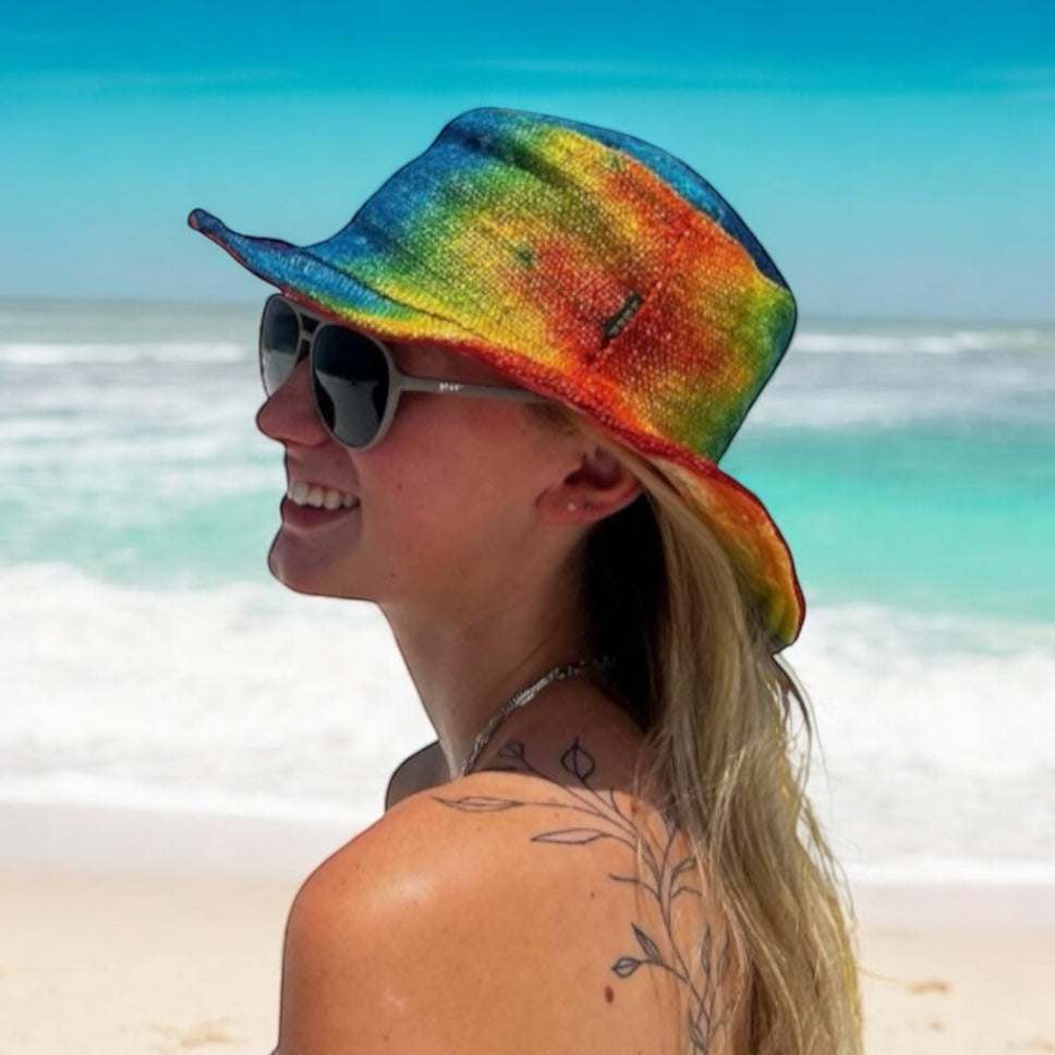 Colorful tie dye hemp rainbow bucket hat on a person at the beach.
