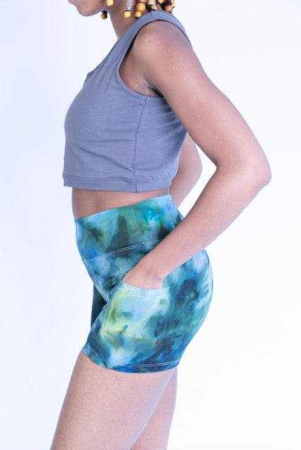 Woman wearing tie dye hemp cotton blend yoga shorts with side pockets and gray sleeveless crop top