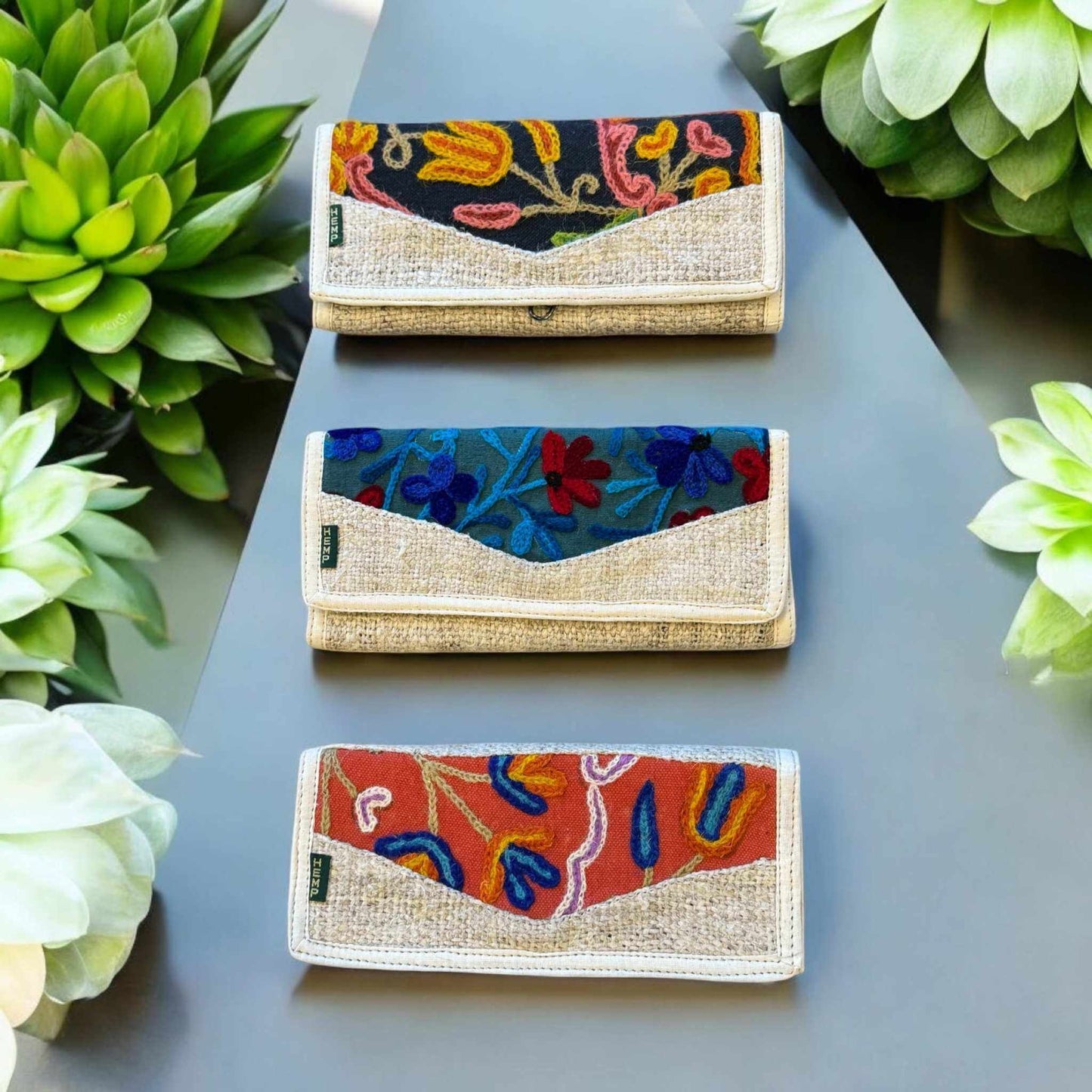 Embroidered hemp wallets with colorful floral designs in sustainable vegan fabric.