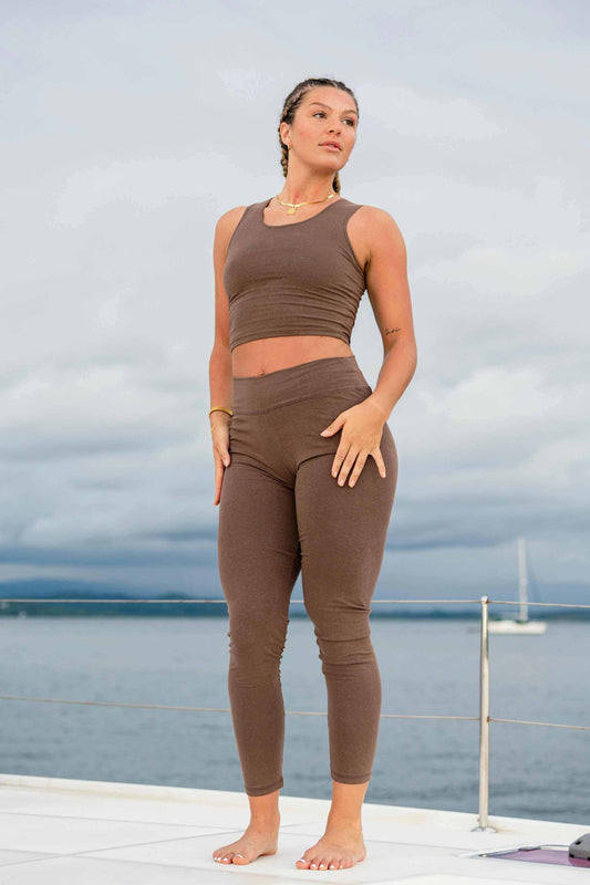 Woman wearing brown premium hemp athletic leggings and matching crop top outdoors by water