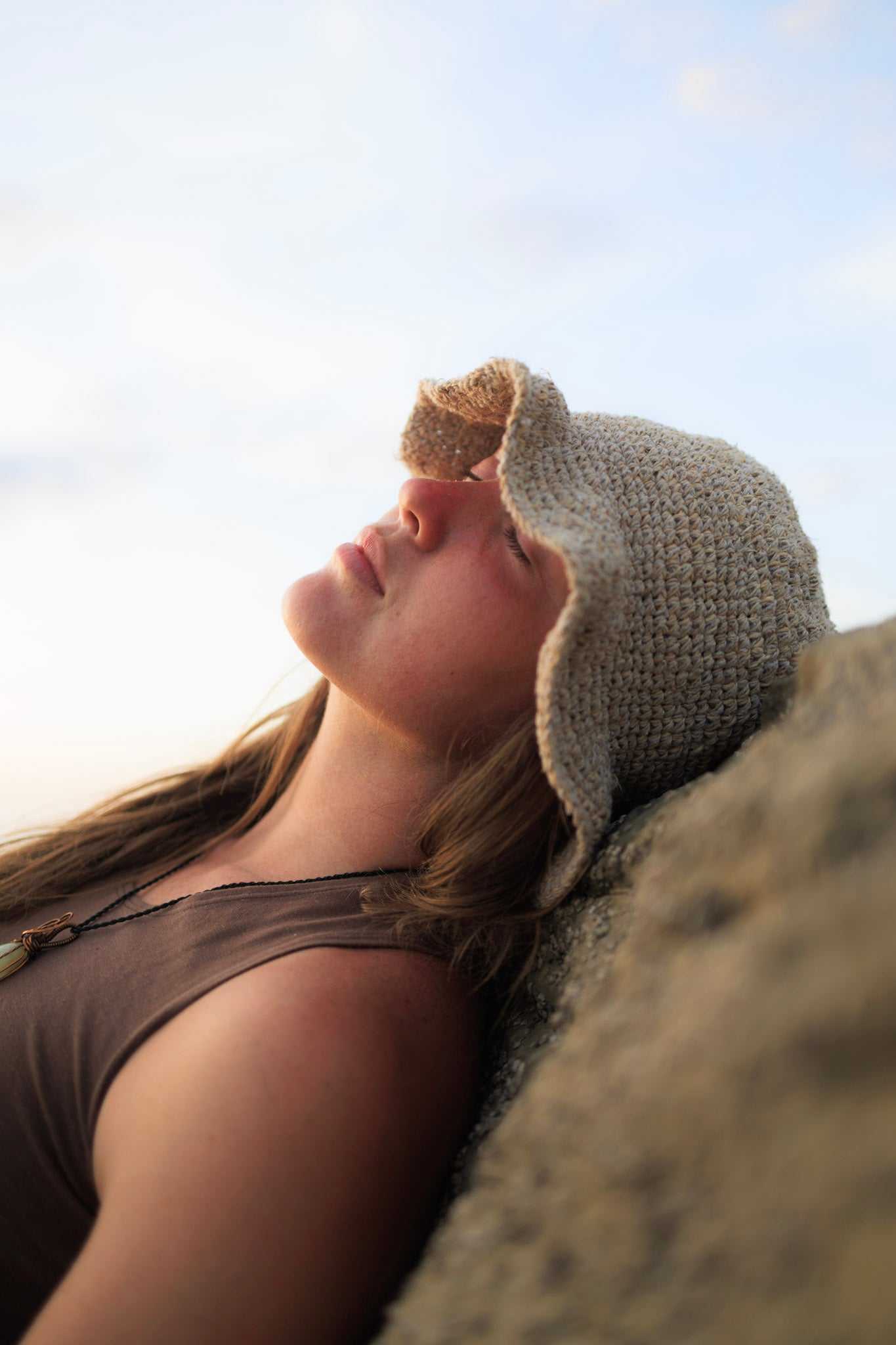 Hand-crocheted hemp floppy beach hat in natural color with wide brim, boho style, and foldable design.