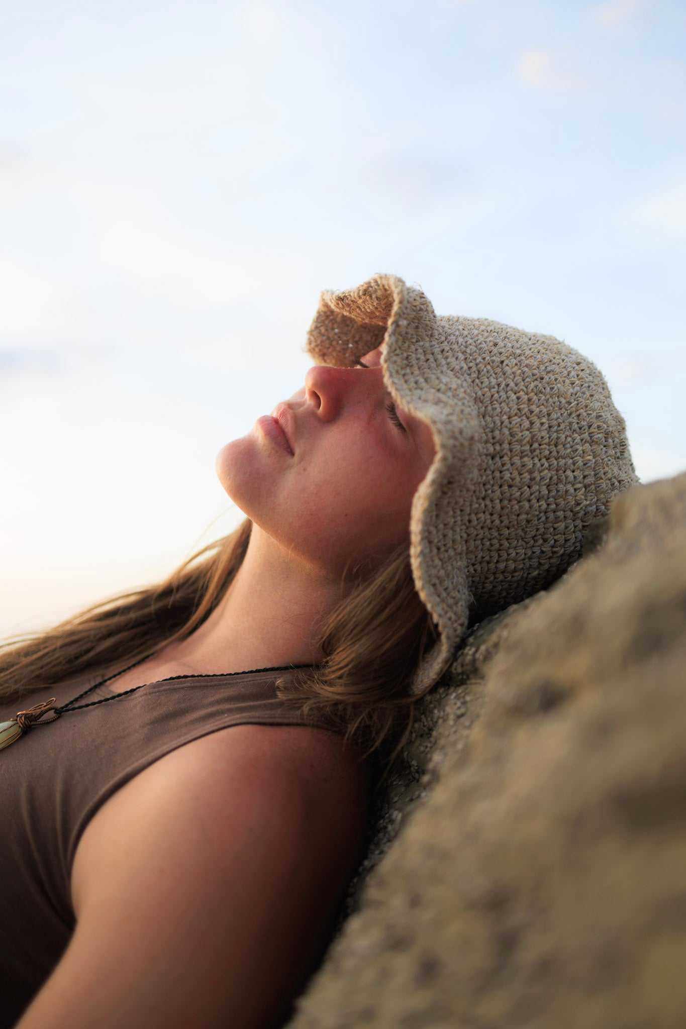 Hand-crocheted hemp floppy beach hat in natural color with wide brim, boho style, and foldable design.