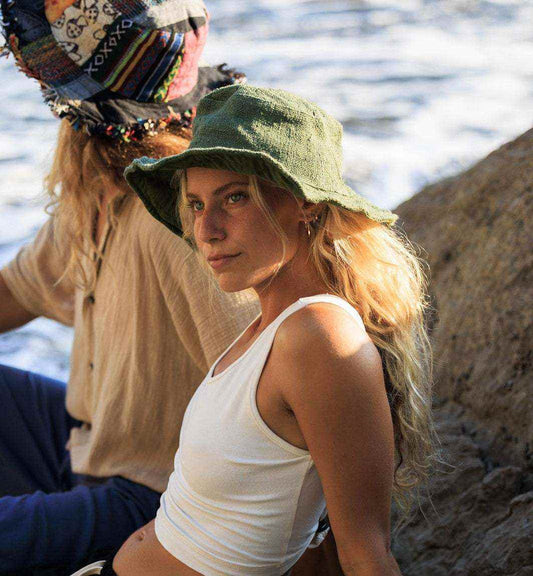 Woman wearing olive green handmade natural hemp hat by the ocean, lightweight and breathable sun protection accessory