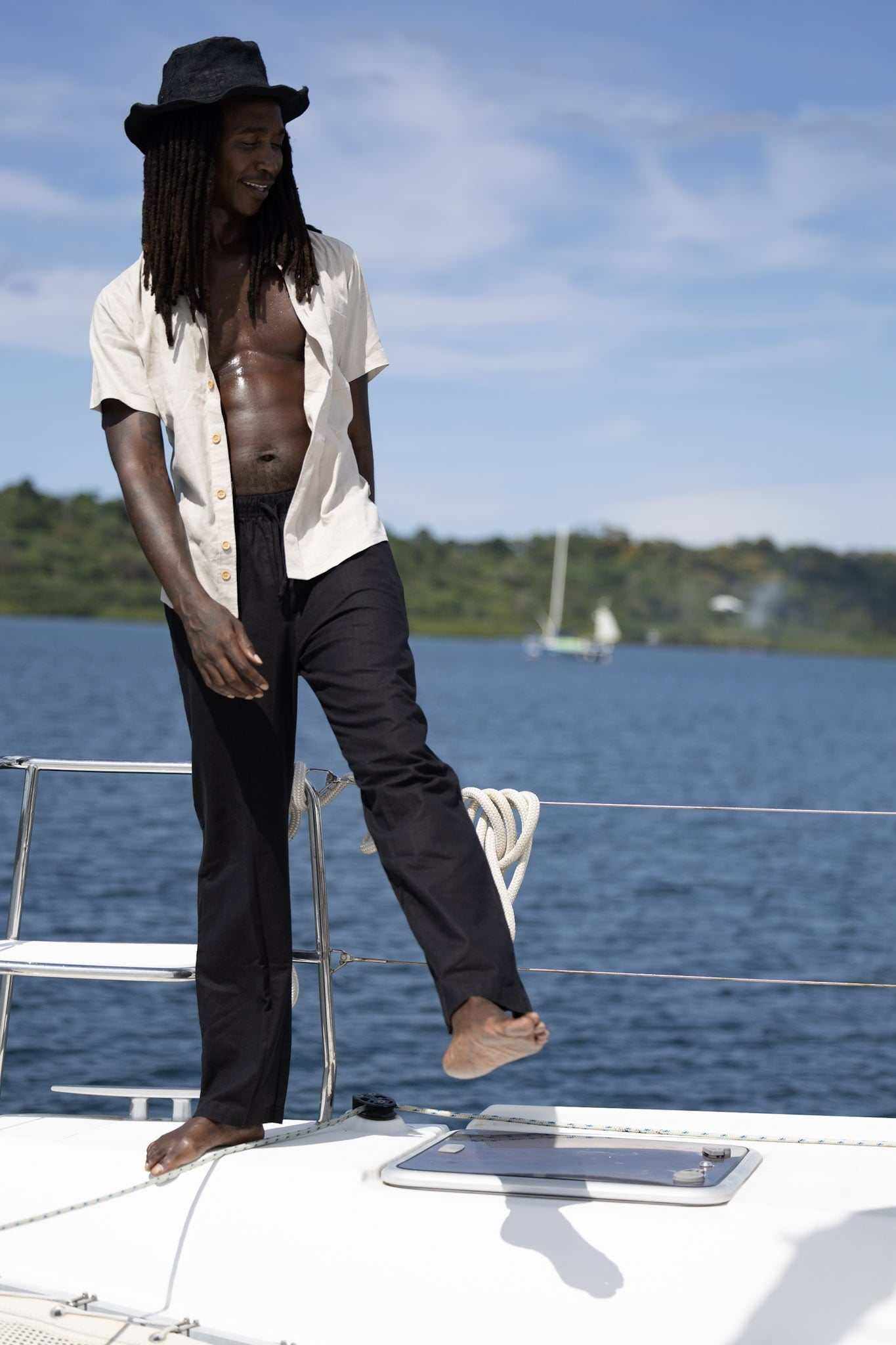 Unisex hemp linen and organic cotton pants in black, worn by a person on a yacht with blue water and sky in the background.