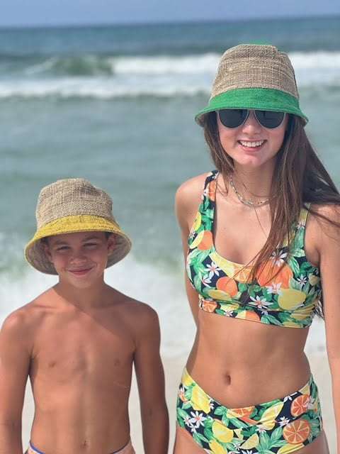 Hemp bucket hat in bright green and yellow worn at the beach.