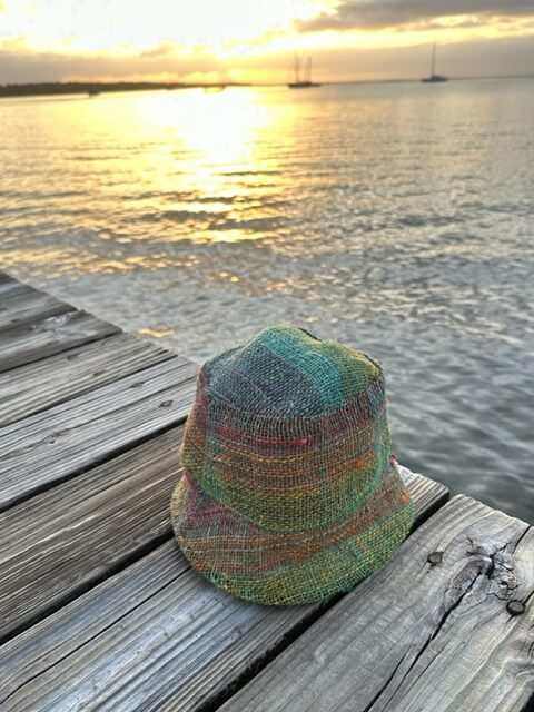 Rainbow hemp bucket hat on woman outdoors, showcasing vibrant colors and sustainable style.