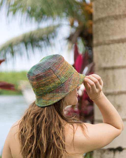 Rainbow hemp bucket hat on woman outdoors, showcasing vibrant colors and sustainable style.