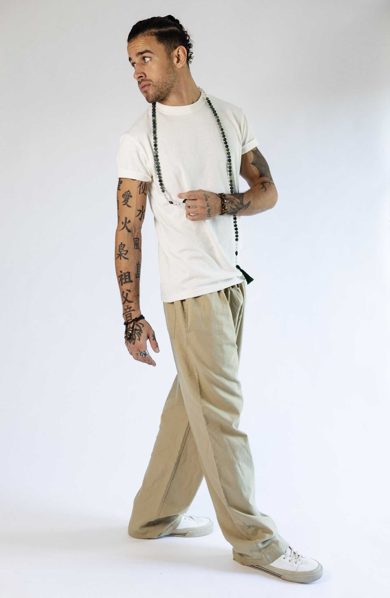Unisex hemp linen and organic cotton pants in taupe with a relaxed fit, shown on a model with tattoos, styled casually.