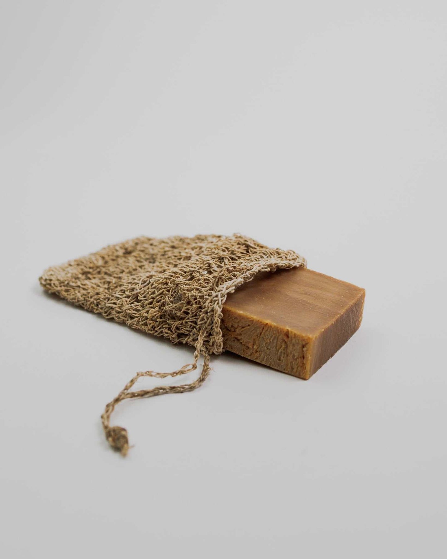 Handmade hemp crocheted soap scrubber holding a rectangular bar of natural soap