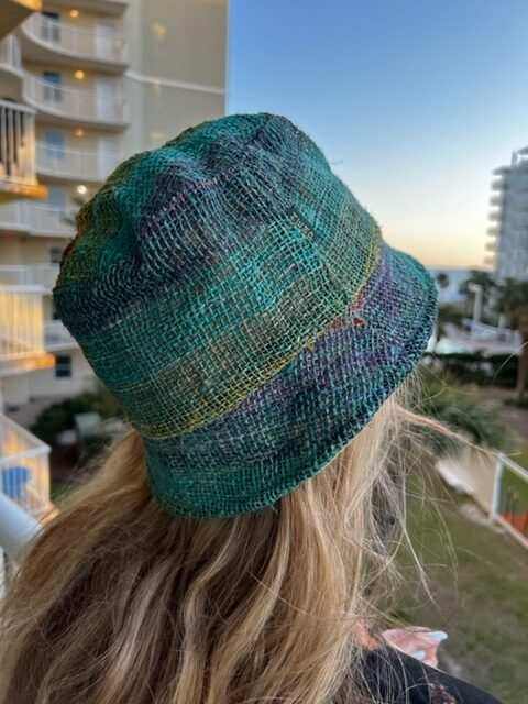 Rainbow hemp bucket hat on woman outdoors, showcasing vibrant colors and sustainable style.