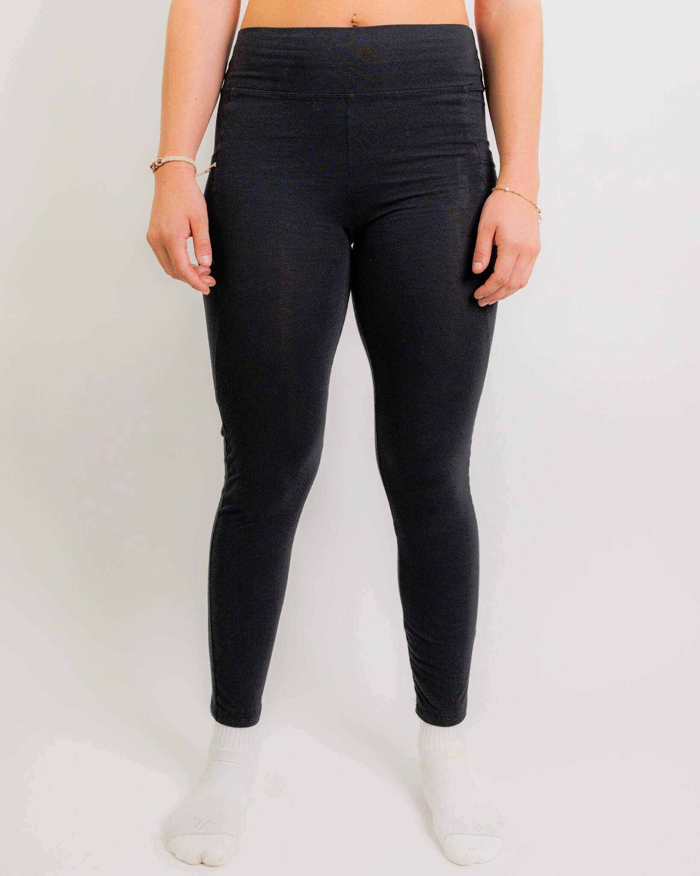 Black high-waisted sustainable hemp and cotton women's leggings with side pockets, worn with white socks.