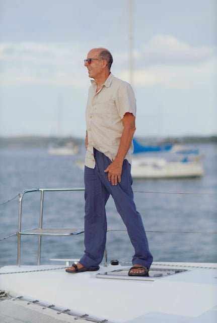 Unisex hemp linen and organic cotton pants in blue worn by a person standing on a boat deck.