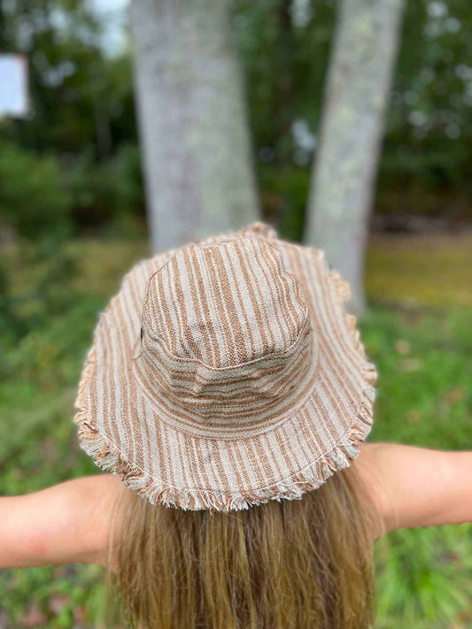 Hemp linen sun hat in neutral tones with a wide brim and frayed edges, worn outdoors.