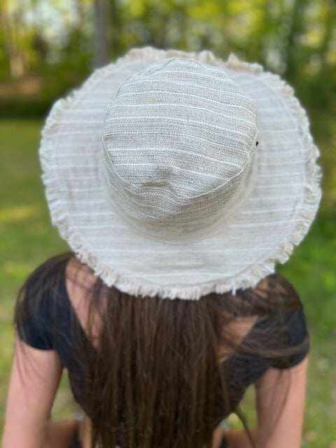 Hemp linen sun hat with neutral stripes and wide brim, worn outdoors.