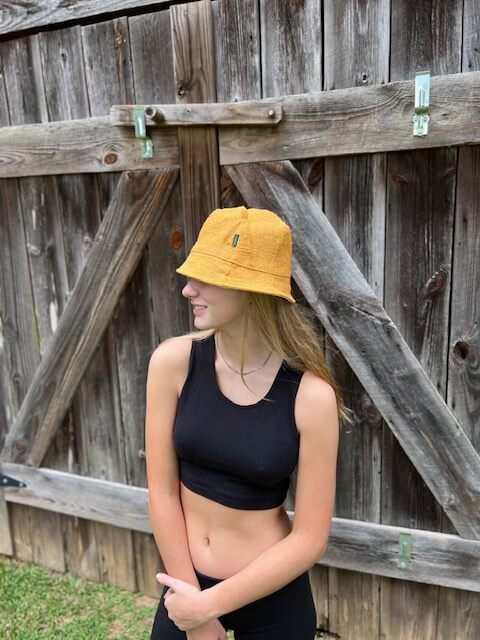 Hemp bucket hats in golden mustard on people at the beach.
