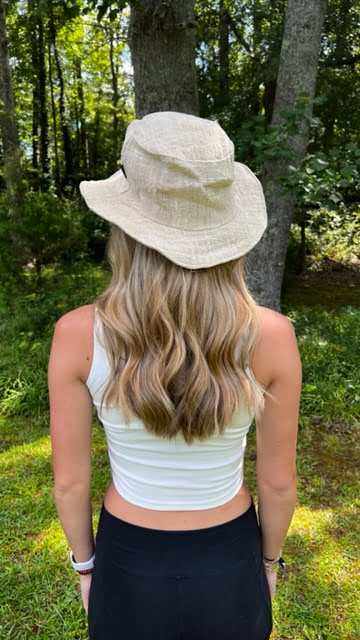 Eco-friendly handmade natural hemp hat with wide brim, worn outdoors by a woman, ideal for sun protection and summer style.