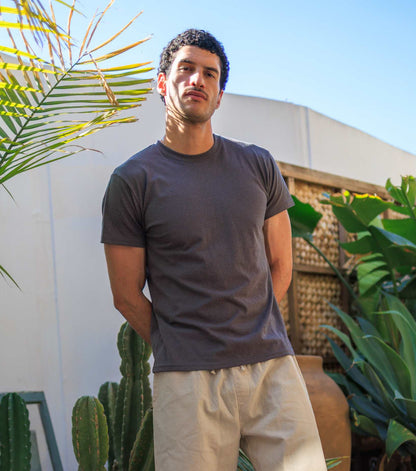 Man wearing lightweight men's hemp t-shirt in outdoor urban setting with plants