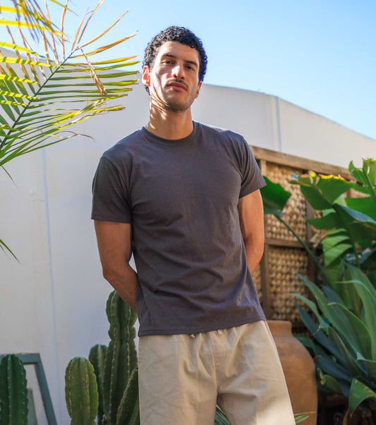 Man wearing lightweight men's hemp t-shirt in outdoor urban setting with plants