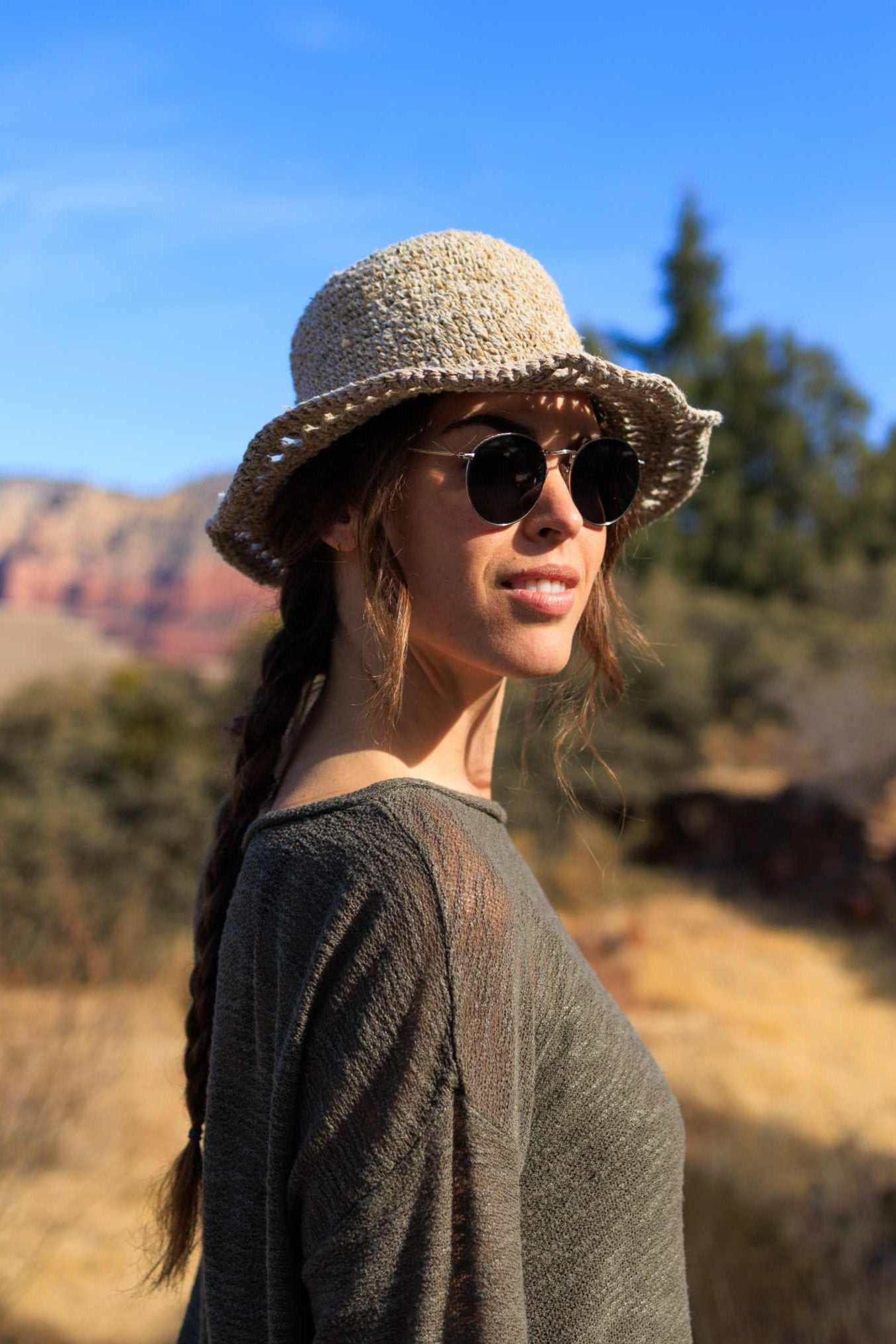 Woman wearing handmade hemp crochet sun hat outdoors with sunglasses and braid hairstyle