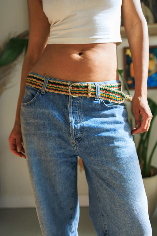 Handmade eco-friendly hemp belt with multi-color red, yellow, green, and blue stripes worn with blue jeans