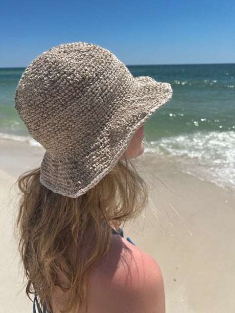 Woman wearing a handmade hemp crochet sun hat with an adjustable wire brim at the beach