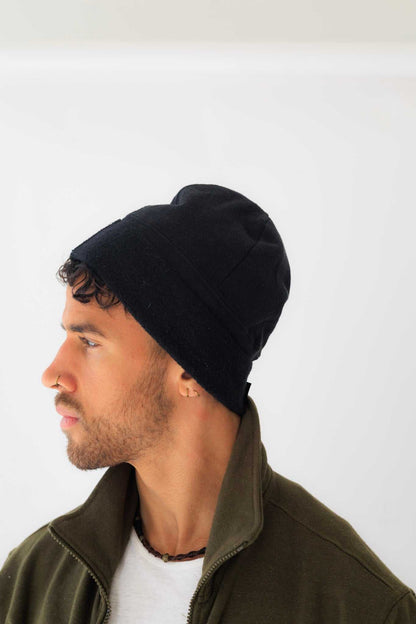 Man wearing a black beanie and green jacket on a white background