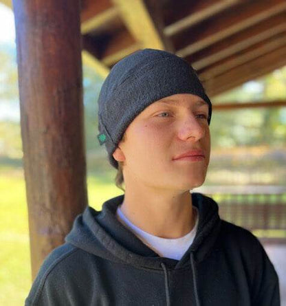 Person wearing a dark gray beanie and hoodie outdoors