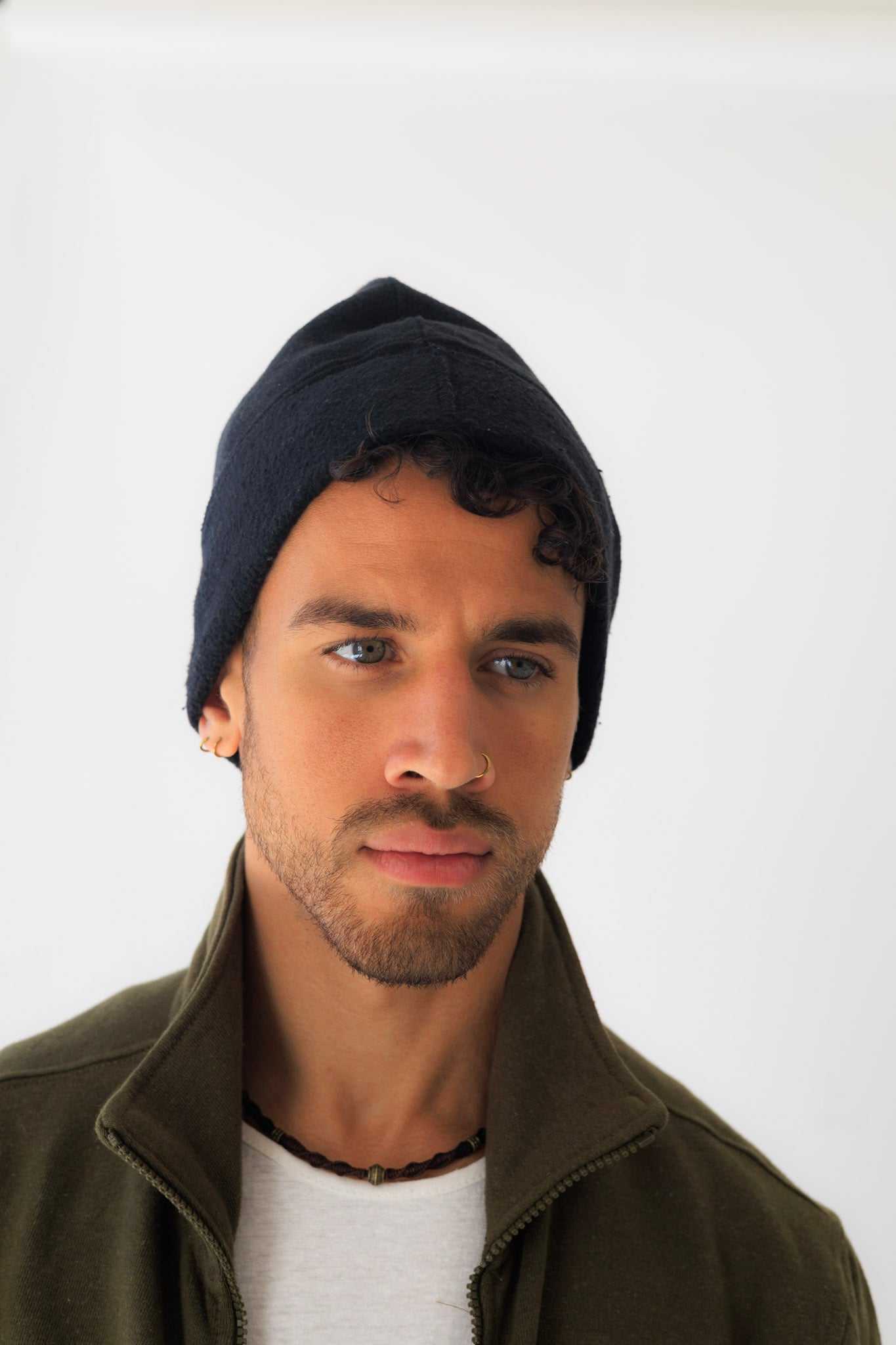 Man wearing a dark beanie and green jacket against a white background