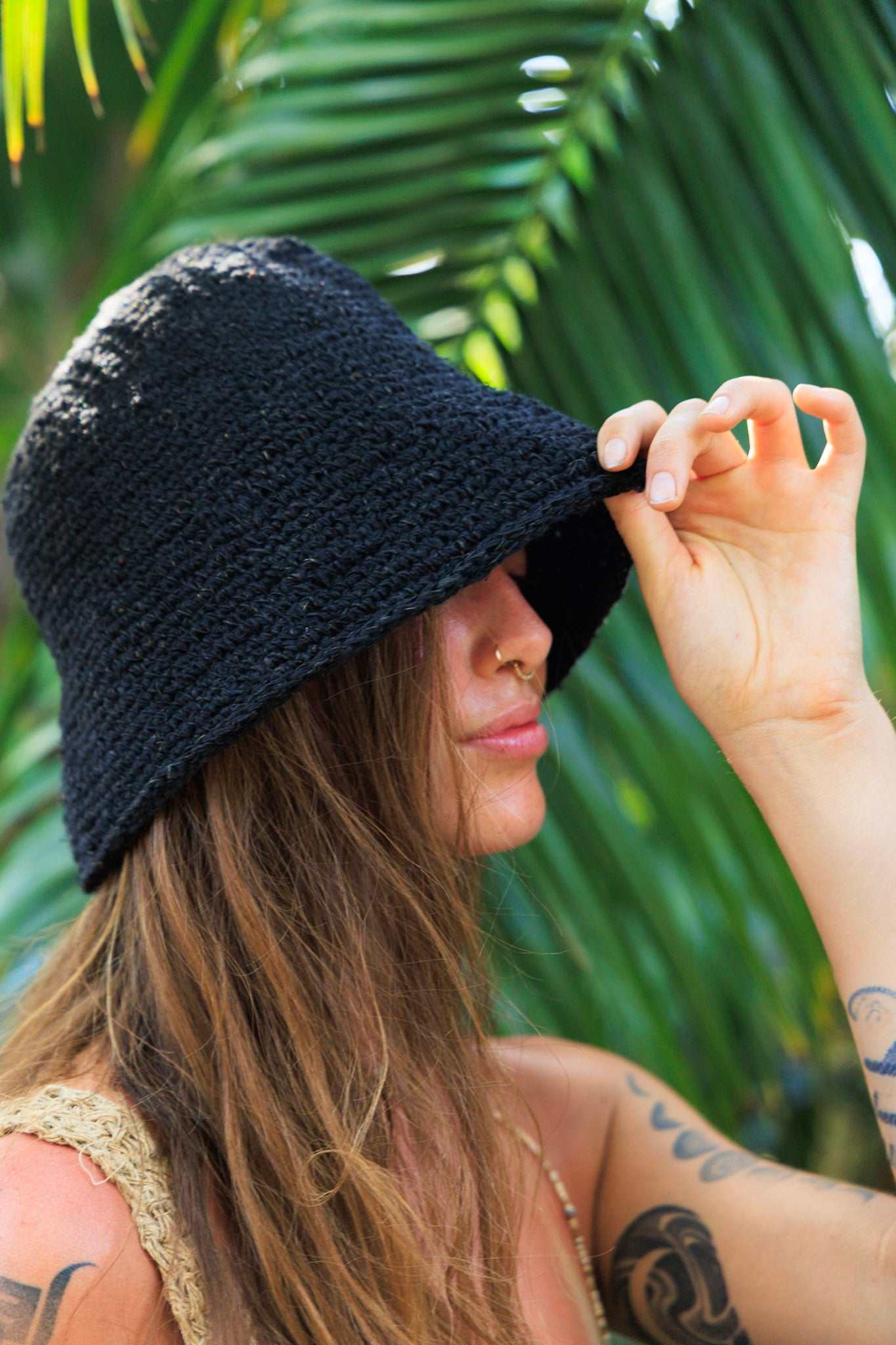 Woman wearing a black bucket hat with green foliage in the background