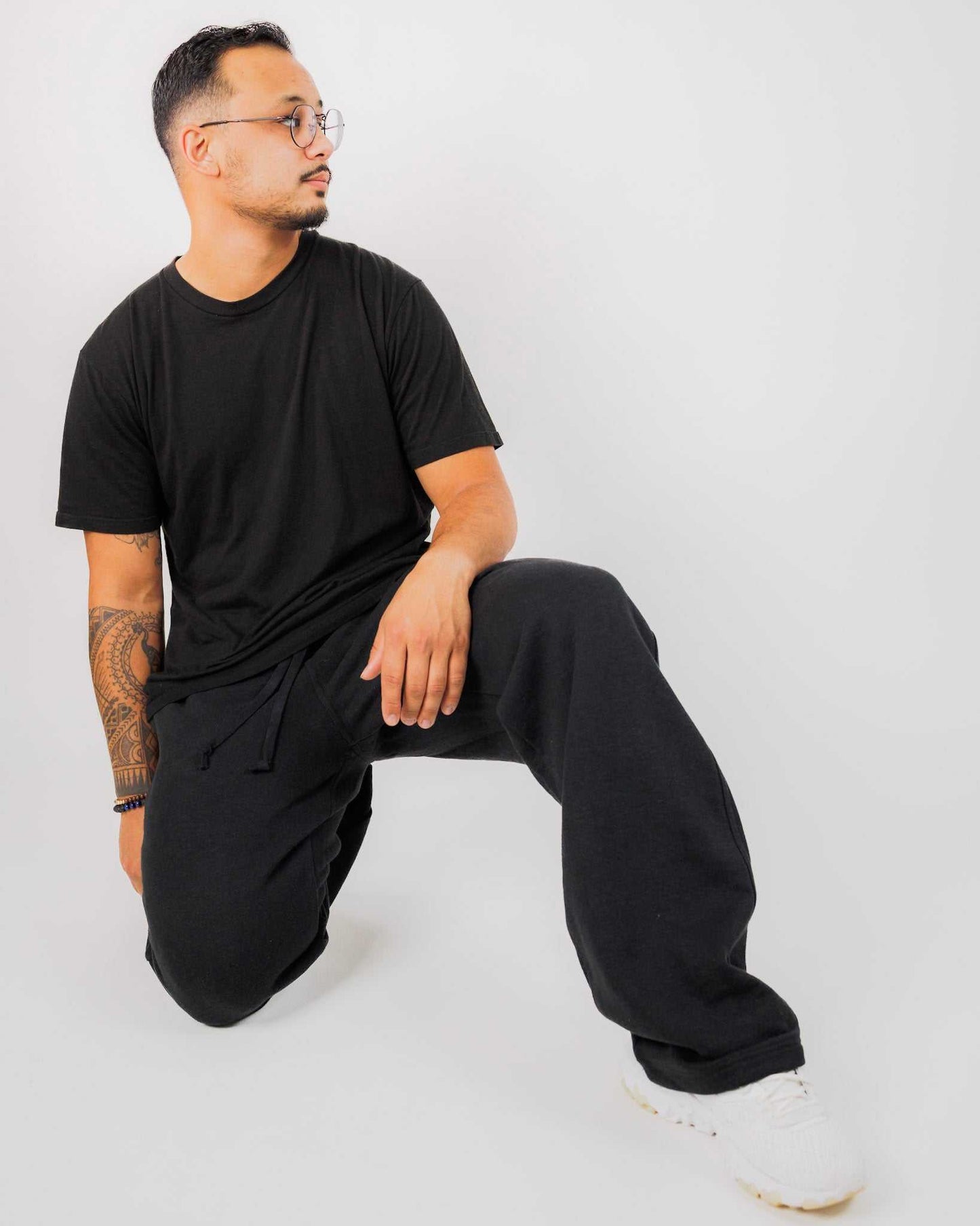 Man wearing a black outfit sitting on a white background