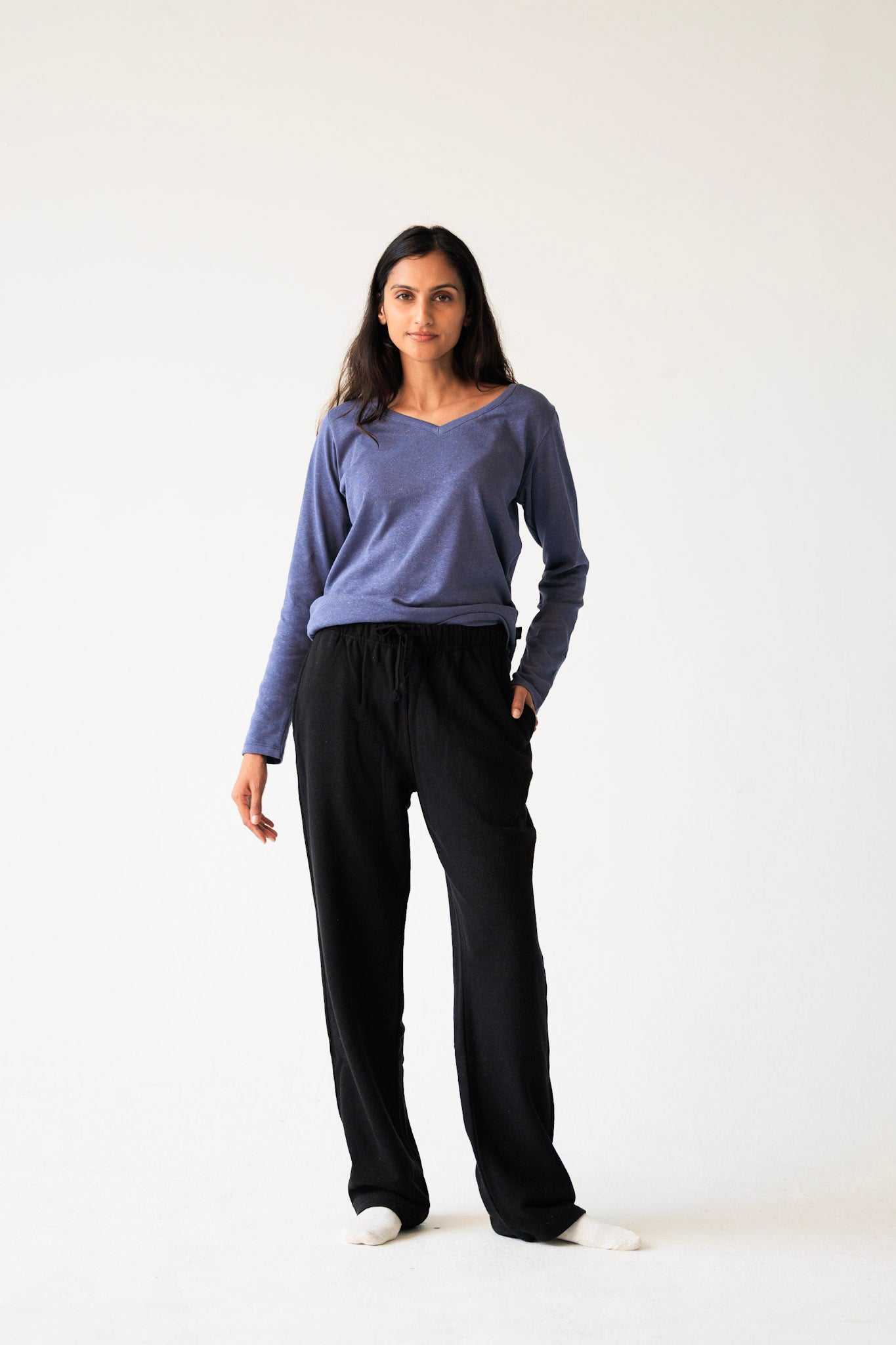Woman wearing a blue top and black pants on a white background