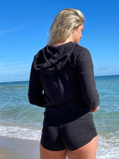 Woman wearing black sustainable hemp and organic cotton zip-up hoodie on beach